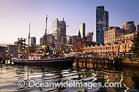 Tall ship, Southern Swan, resting in Campbell's Cove during sunrise, with historic The Rocks buildings in the background. Sydney, New South Wales, Australia