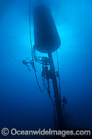 Divers work to install a massive wave energy buoy off Kaneoho Bay, Oahu. The 40-kW experimental buoy, employs the bobbing motion of the buoy to drive an electrical generator, that then sends power to the island via underwater cable, Hawaii.