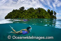 Under Over image of a Snorkel Diver exploring a tropical Island coral reef. Kimbe Bay, Papua New Guinea.