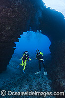 Scuba Divers exploring an archway at divesite First Cathedral, situated off the Island of Lanai, Hawaii, Pacific Ocean.